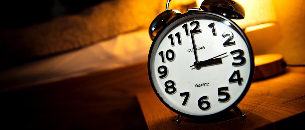 Eine Uhr steht neben einem Bett. Am letzten Sonntag im Oktober beginnt die sogenannte Winterzeit, dabei werden die Uhren zurückgestellt.