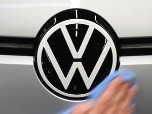 Eine Mitarbeiterin wischt über das VW-Logo auf einem ID.3 in der Monatgelinie im Werk von Volkswagen in Zwickau. 