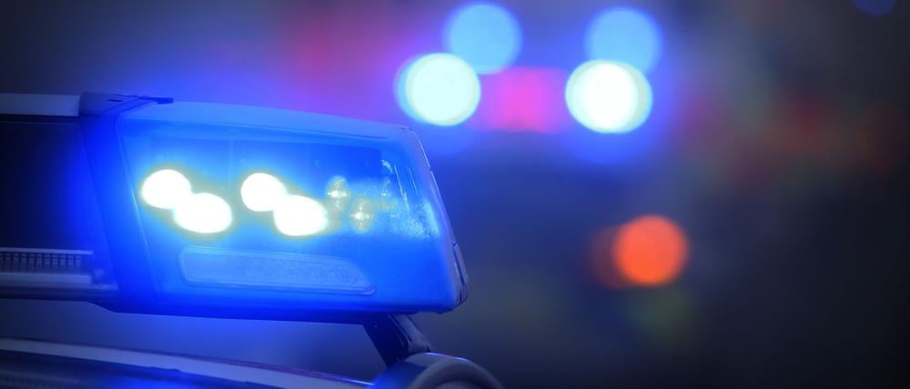 Ein Polizeiauto mit eingeschaltetem Blaulicht steht an einer Unfallstelle.