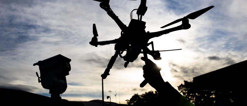 Ein DLR-Mitarbeiter hält eine Drohne vor einem Fahrzeug zur Drohnendetektion auf dem Gelände vom DLR Deutsches Zentrum für Luft- und Raumfahrt bei der Eröffnung des Drohnentestfelds Flybots.