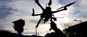 Ein DLR-Mitarbeiter hält eine Drohne vor einem Fahrzeug zur Drohnendetektion auf dem Gelände vom DLR Deutsches Zentrum für Luft- und Raumfahrt bei der Eröffnung des Drohnentestfelds Flybots. 