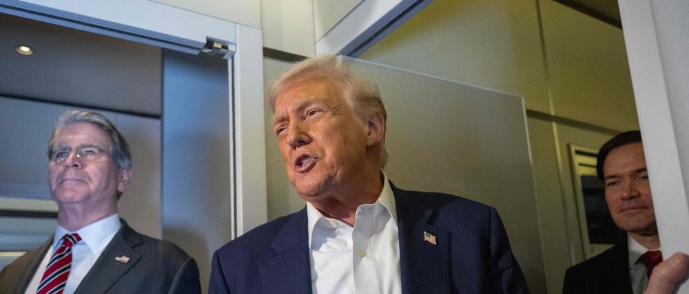 US-Präsident Donald Trump spricht, während US-Finanzminister Scott Bessent (links) und US-Außenminister Marco Rubio (rechts) zusehen, wie er an Bord der Air Force One auf dem Weg nach Japan am 27. Oktober 2025 mit den Medien spricht.