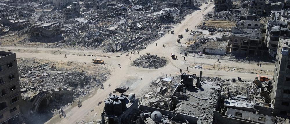 Auf diesem Drohnenfoto gehen Palästinenser über eine Kreuzung, die von Gebäuden umgeben ist, die während der zweijährigen Bombardierung durch die israelische Armee in der Stadt zerstört wurden.