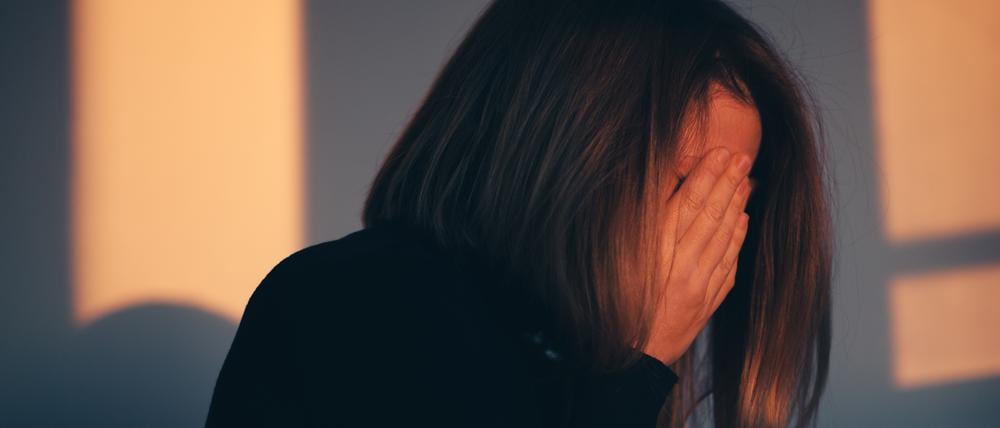 A woman sitting alone and depressed in window light