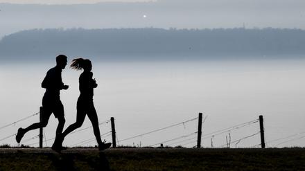 Zusammen laufen: Eine Frau und ein Mann joggen auf einem Wanderweg.