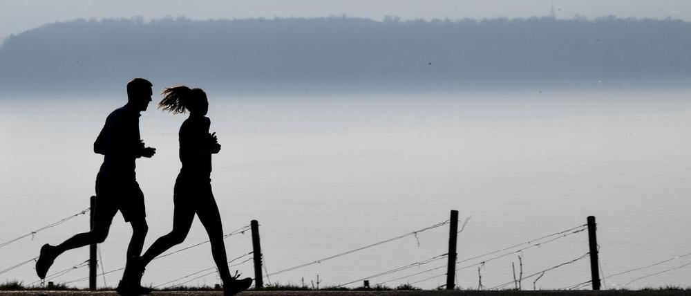 Zusammen laufen: Eine Frau und ein Mann joggen auf einem Wanderweg.