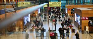 Zahlreiche Menschen gehen am Flughafen BER zur Sicherheitskontrolle. 