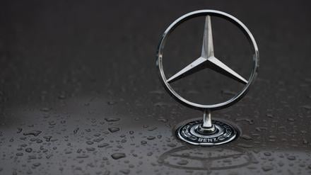 Regentropfen sind auf einem Mercedes-Stern auf einem Fahrzeug zu sehen.