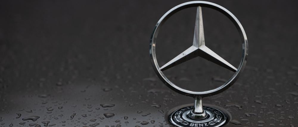Regentropfen sind auf einem Mercedes-Stern auf einem Fahrzeug zu sehen.