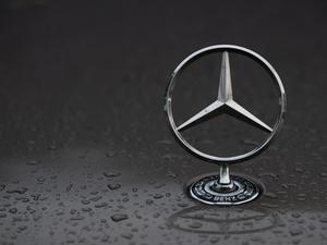 Regentropfen sind auf einem Mercedes-Stern auf einem Fahrzeug zu sehen.