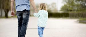 Ein Kind geht an der Hand eines Mannes.