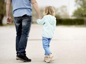 Ein Kind geht an der Hand eines Mannes.