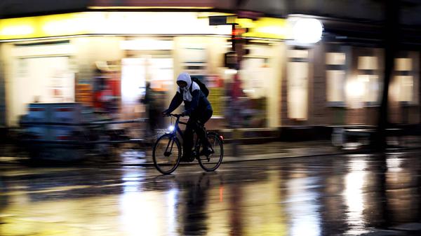 Ein Radler fährt im Regen bei Nacht. (Symbolbild)