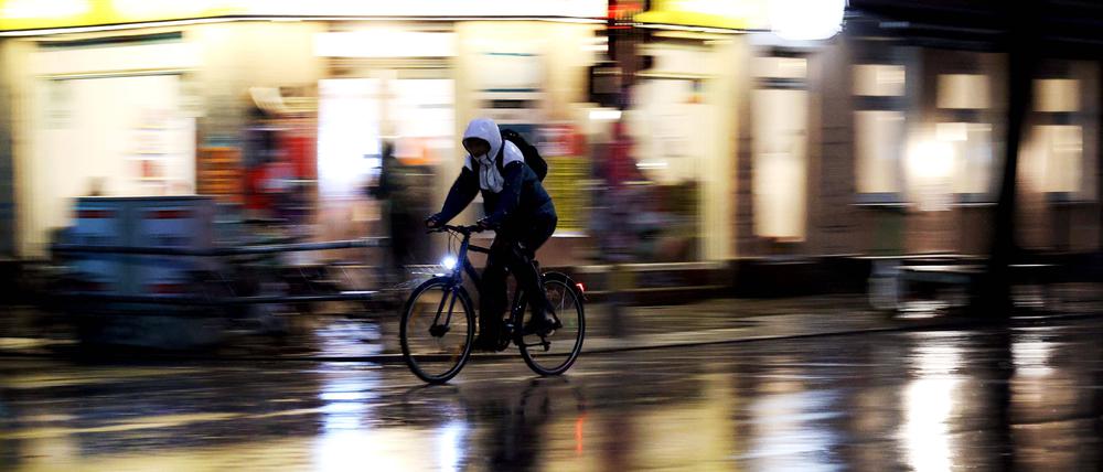 Ein Radler fährt im Regen bei Nacht. (Symbolbild)