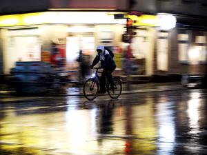 Ein Radler fährt im Regen bei Nacht. (Symbolbild)