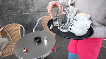 Ein Kellner räumt einen Tisch in einem Café ab.