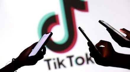 Hände mit Smartphones vor Tiktok-Logo.