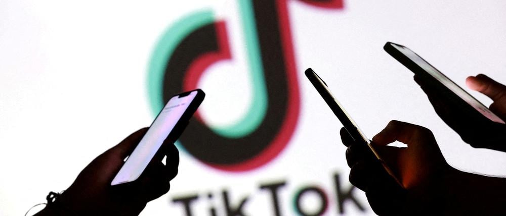 Hände mit Smartphones vor Tiktok-Logo.