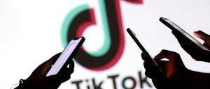 Hände mit Smartphones vor Tiktok-Logo.