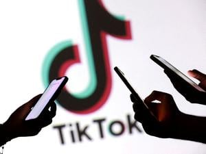 Hände mit Smartphones vor Tiktok-Logo.