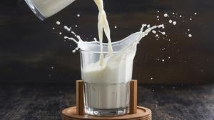 Milch wird aus einer Wasserkaraffe in ein Glas geschüttet.