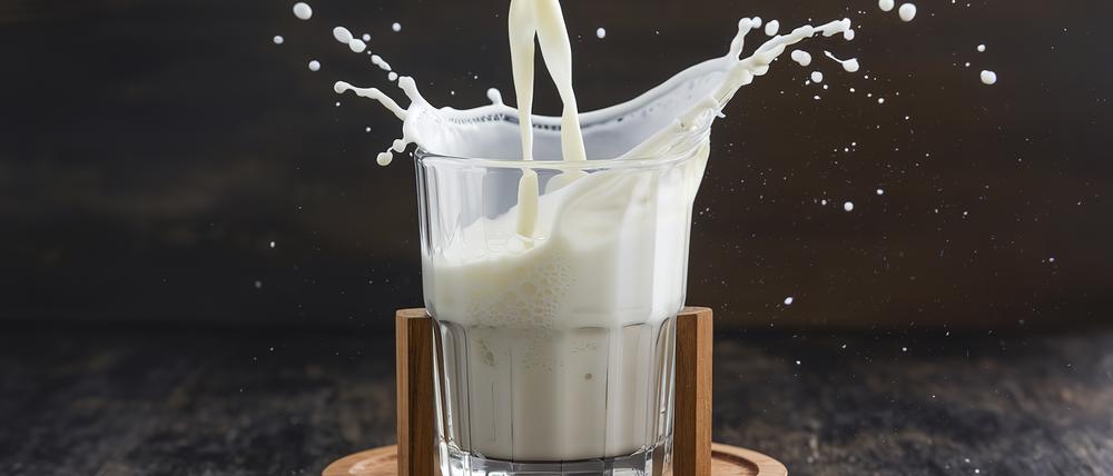 Milch wird aus einer Wasserkaraffe in ein Glas geschüttet.