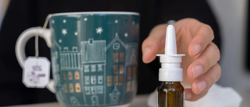 Eine Frau greift nach Nasenspray.