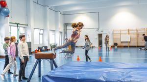 Kinder beim Bocksprung in einer Turnhalle.