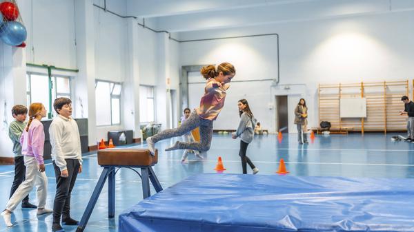 Kinder beim Bocksprung in einer Turnhalle.