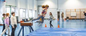 Kinder beim Bocksprung in einer Turnhalle.