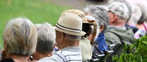 Ältere Menschen besuchen in einem Kurpark das Konzert eines Schulorchesters. 