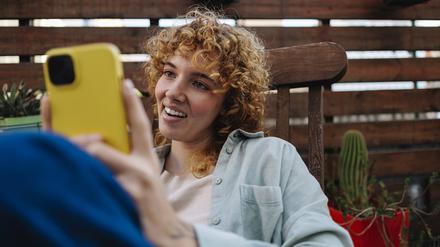 Eine junge Frau schaut sich Tiktok auf dem Handy an.