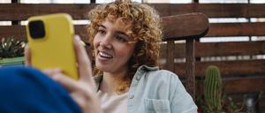 Eine junge Frau schaut sich Tiktok auf dem Handy an.