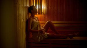 Eine Frau sitzt in einer Sauna.