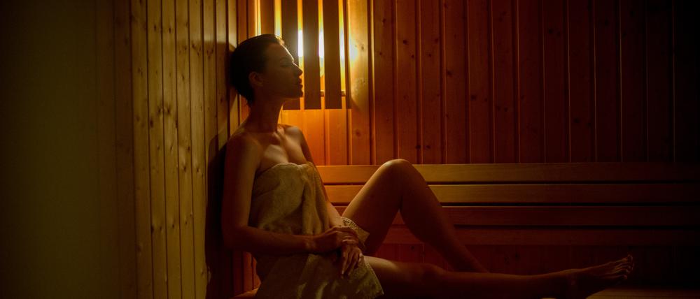 Eine Frau sitzt in einer Sauna.