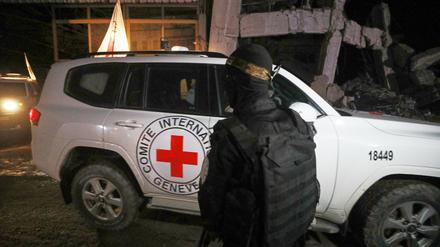 Ein bewaffneter Mann in der Uniform der al-Qassam-Brigaden, dem militärischen Flügel der Hamas, steht Wache, als Fahrzeuge des Roten Kreuzes ein Lagerhaus verlassen (Symbolfoto).