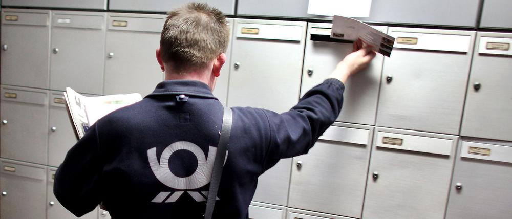 Ein Briefträger der Deutschen Post trägt Briefe aus (Symbolbild).
