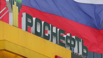 Das Logo des Konzerns Rosneft vor einer russischen Flagge.
