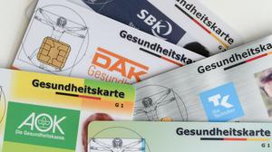 Gesundheitskarten verschiedener Krankenkassen liegen auf einem Tisch.