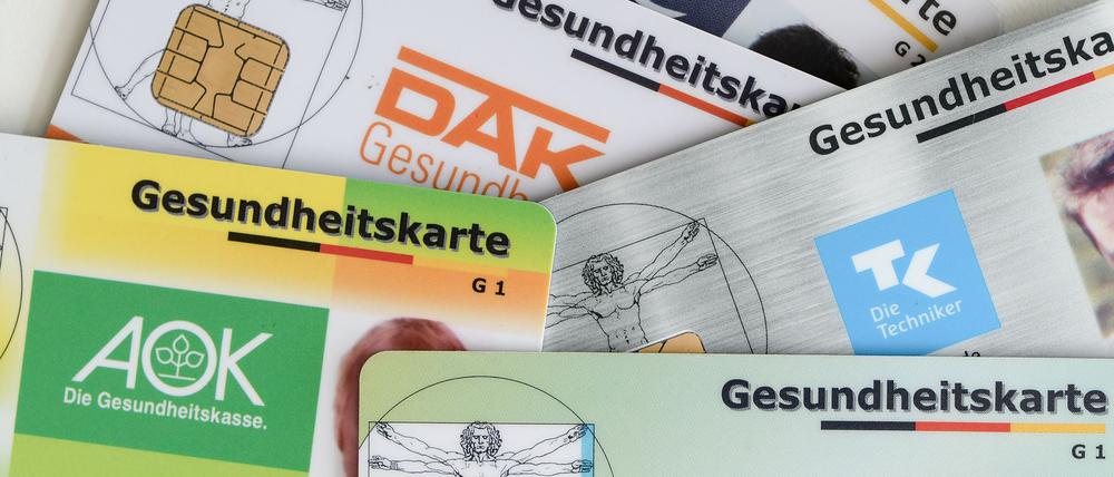 Gesundheitskarten verschiedener Krankenkassen liegen auf einem Tisch.