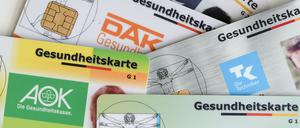 Gesundheitskarten verschiedener Krankenkassen liegen auf einem Tisch.