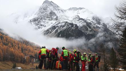 Mitglieder der Bergrettung warten vor den verschneiten Bergen des Ortler Gebirges auf den Rettungshubschrauber. 