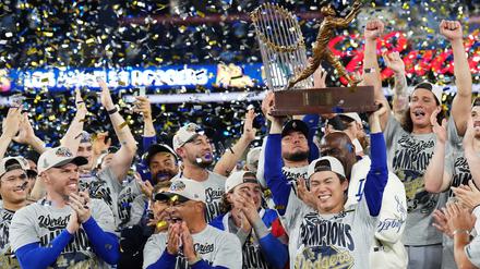 Der Pitcher der Los Angeles Dodgers, Yoshinobu Yamamoto (rechts), hebt die MVP-Trophäe der World Series in die Höhe, während die Dodgers nach dem Sieg über die Toronto Blue Jays feiern.