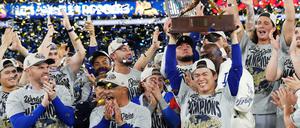 Der Pitcher der Los Angeles Dodgers, Yoshinobu Yamamoto (rechts), hebt die MVP-Trophäe der World Series in die Höhe, während die Dodgers nach dem Sieg über die Toronto Blue Jays feiern.