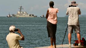 Schaulustige beobachten und fotografieren den Zerstörer USS Gravely, der einen Hafen von Trinidad und Tobago verlässt.