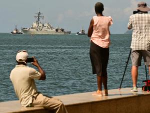 Schaulustige beobachten und fotografieren den Zerstörer USS Gravely, der einen Hafen von Trinidad und Tobago verlässt.