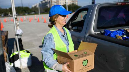 Die Freiwillige Nikki Wagner hält ein Essenspaket in der Hand.