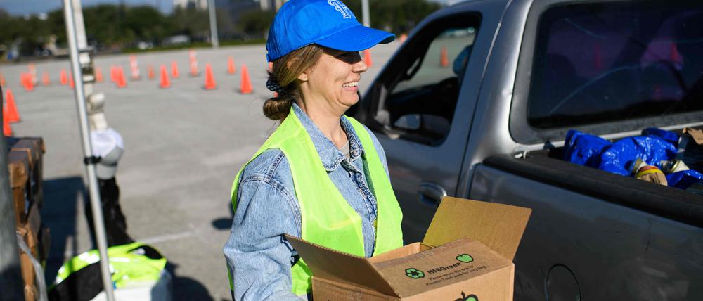 Die Freiwillige Nikki Wagner hält ein Essenspaket in der Hand.