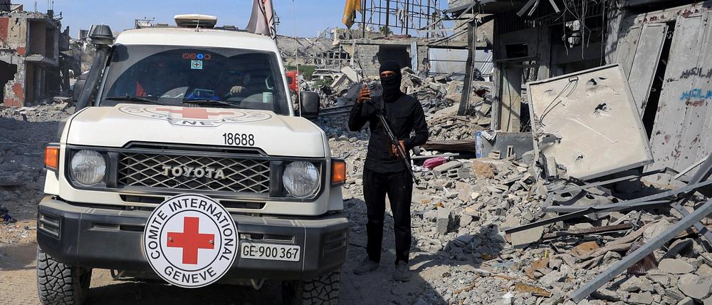 Ein palästinensischer Hamas-Kämpfer steht Wache, während Mitarbeiter des Roten Kreuzes sich einem Gebiet innerhalb der sogenannten „gelben Linie“ nähern, in das sich israelische Truppen im Rahmen des Waffenstillstands zurückgezogen haben (Gaza, 2. November).