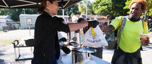 Die freiwillige Helferin Antonia Uribe (l) verteilt Tüten mit Lebensmitteln bei einer Lebensmittelausgabe der Village (FREE)DGE im Freedom Lab, einer gemeinnützigen Initiative.